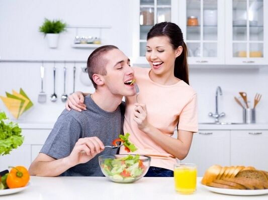 The girl feeds her man with products to increase her strength. 